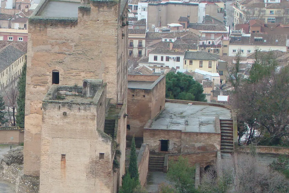 Two tall brick and rammed-earth towers with a flat roof and stone stairs, seen from above with Granada's rooftops behind